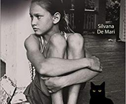 Foto di bambina seduta con le gambe tra le braccia e gatto nero